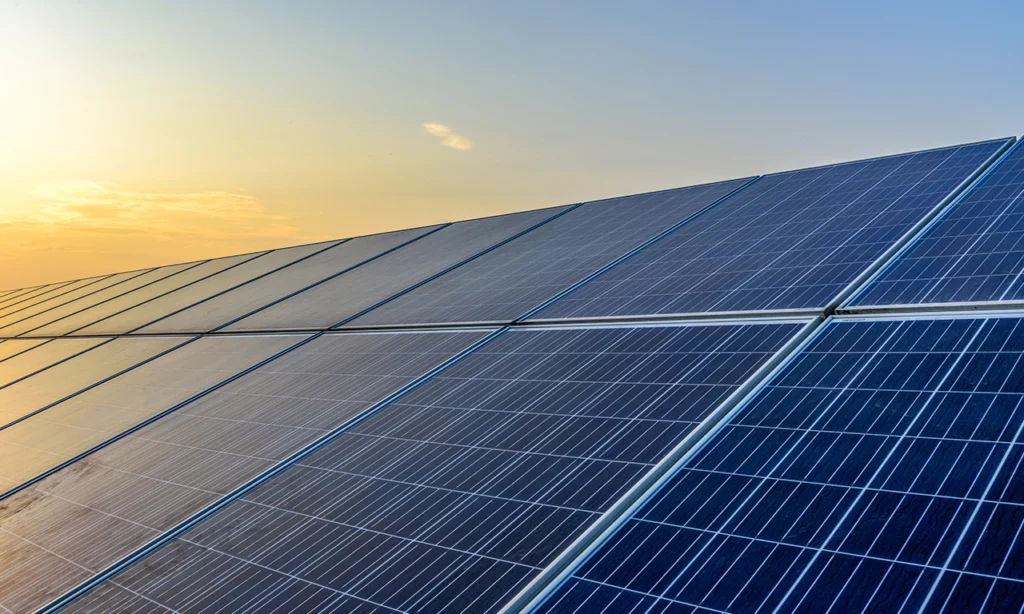 Painéis solares fotovoltaicos captando luz do sol ao entardecer, ilustrando como funciona um sistema fotovoltaico